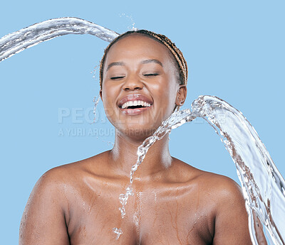 Buy stock photo Studio shot of an attractive young woman being splashed with water against a blue background