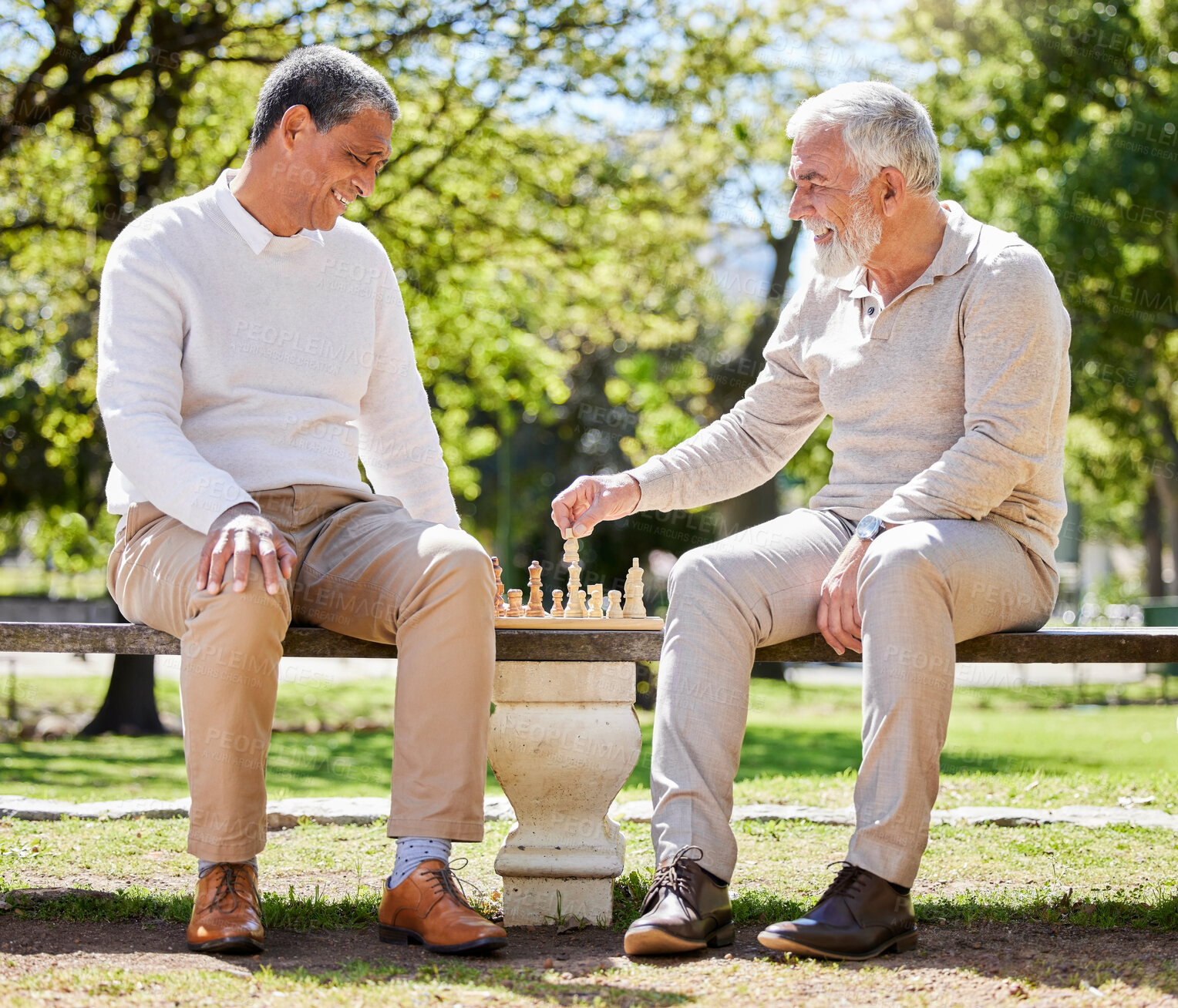 Buy stock photo Full length shot of two men sitting outside together and playing a game of chess