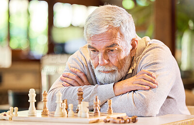 Buy stock photo Shot of a senior man sitting alone inside and looking contemplative while playing a game of chess