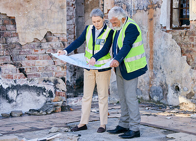 Buy stock photo Shot of two  engineers looking at blueprints while standing on a construction site