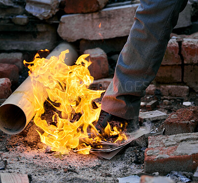 Buy stock photo Shot of a unrecognizable man stepping on a burning paper inside a burned down house