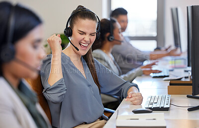 Buy stock photo Shot of a young call centre agent cheering while working alongside her colleagues in an office