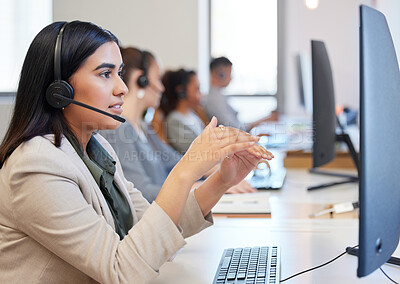Buy stock photo Shot of a young call centre agent working in an office with her colleagues in the background