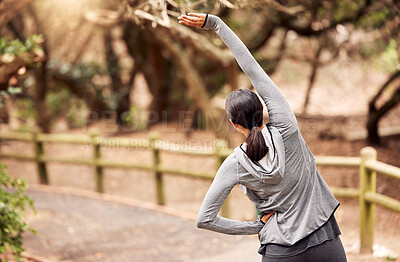 Buy stock photo Rearview shot of a young woman stretching before her workout in nature