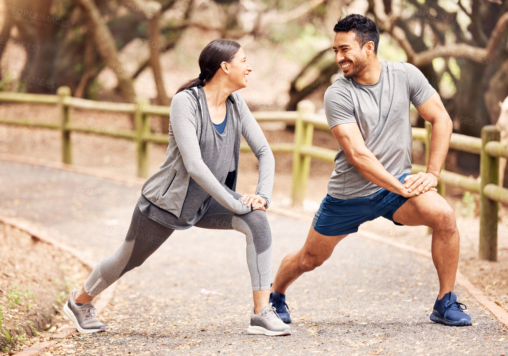 Buy stock photo Shot of a young couple stretching before their workout in nature