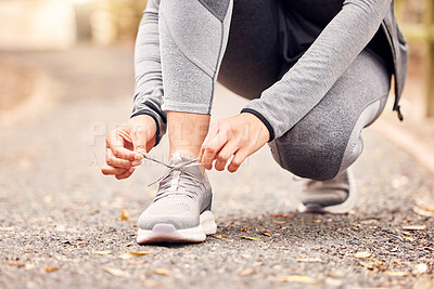 Buy stock photo Shot of an unrecognisable woman tying her shoelaces before going for a run in nature