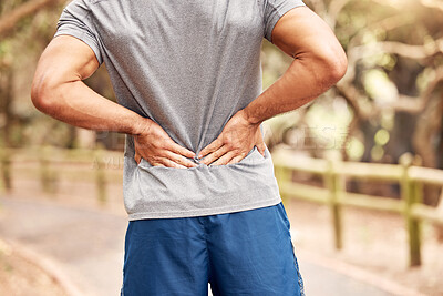 Buy stock photo Shot of an unrecognisable man experiencing back pain while working out in nature