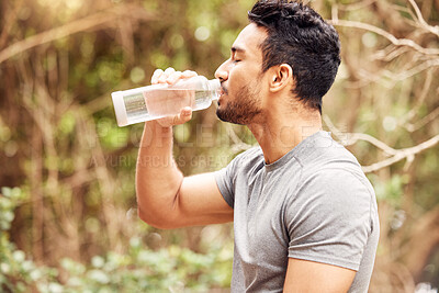Buy stock photo Shot of a fit young man drinking water after his workout in nature