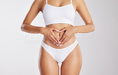 Buy stock photo Cropped shot of a woman forming a heart shape over her stomach