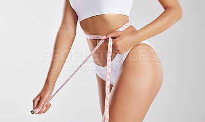 Buy stock photo Studio shot of a fit young woman measuring her waist
