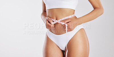 Buy stock photo Studio shot of a fit young woman measuring her waist