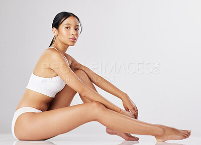 Buy stock photo Shot of a fit young woman sitting against a studio background in her underwear