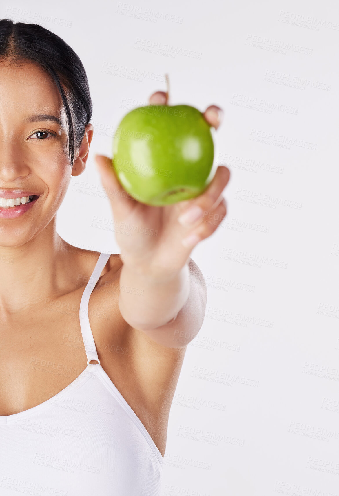 Buy stock photo Shot of a healthy young woman holding an apple while posing against a studio background