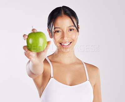 Buy stock photo Shot of a healthy young woman holding an apple while posing against a studio background