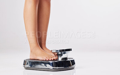 Buy stock photo Cropped shot of a young woman standing on a weight scale