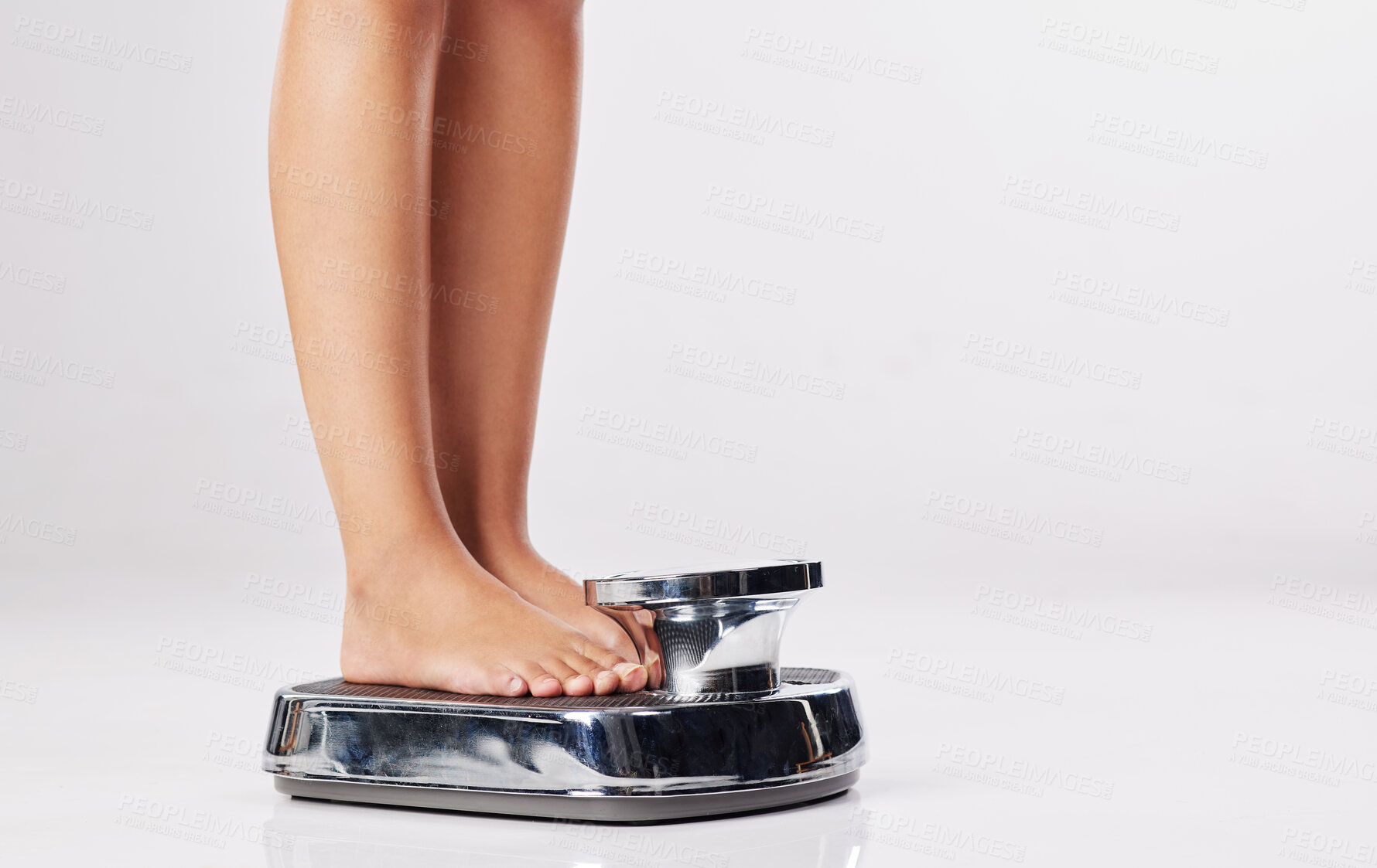 Buy stock photo Cropped shot of a young woman standing on a weight scale