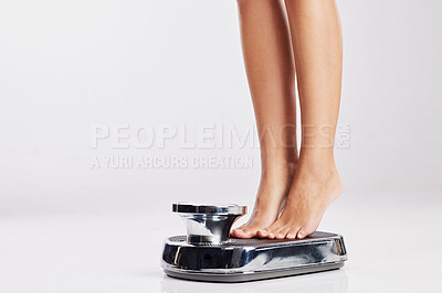 Buy stock photo Cropped shot of a young woman standing on a weight scale