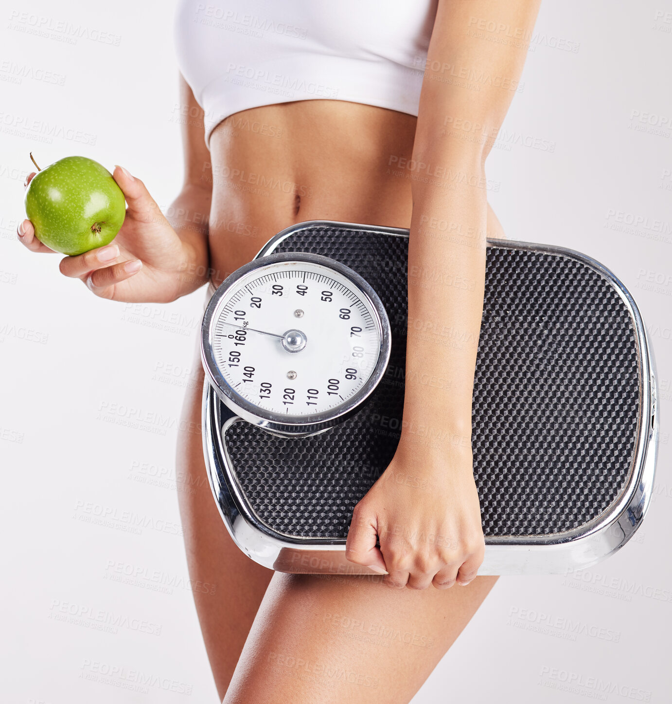 Buy stock photo Shot of a healthy young woman holding an apple and a weight scale