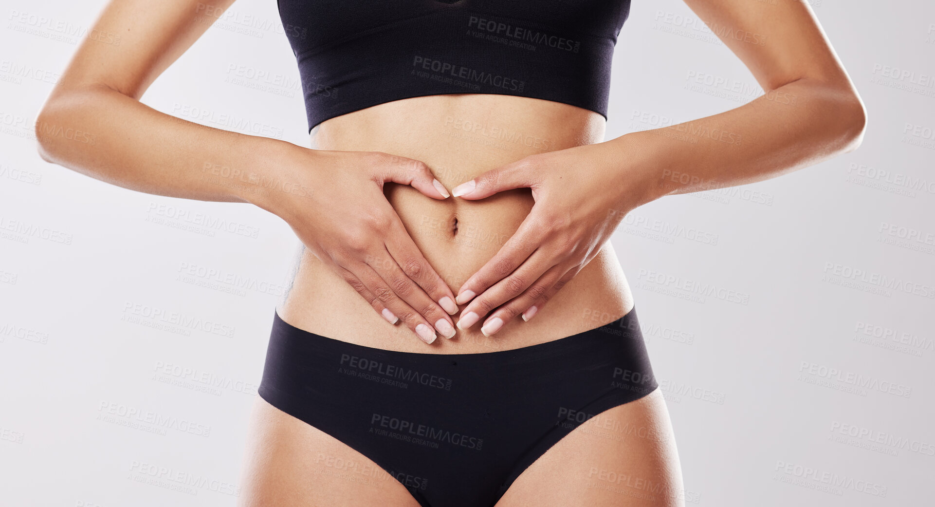 Buy stock photo Cropped shot of a woman forming a heart shape over her stomach