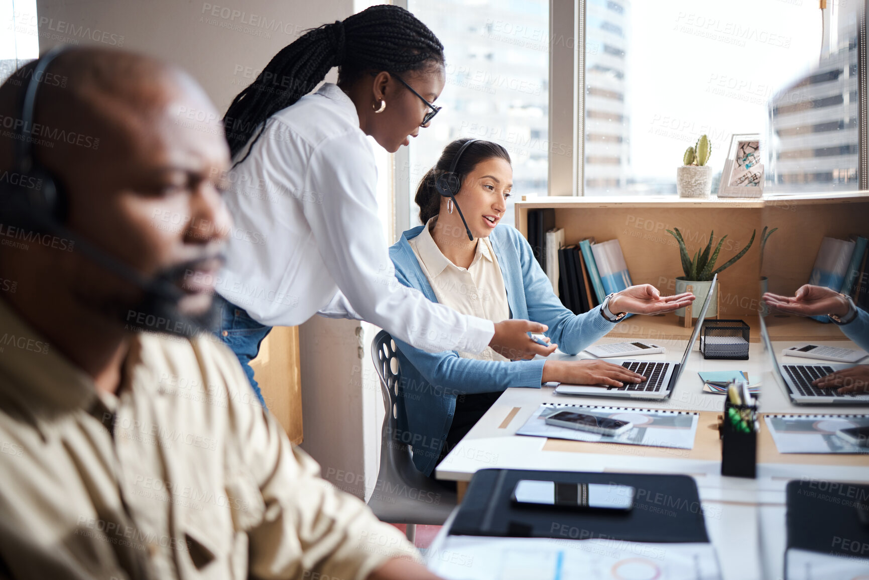 Buy stock photo Shot of two businesswomen using a headset and computer while working in a modern office