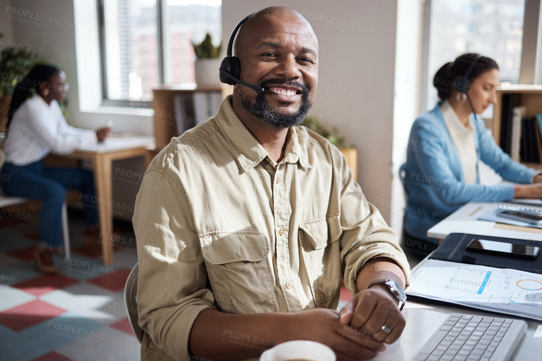 Buy stock photo Shot of a mature businessman using a headset in a modern office with his colleague working in the background