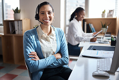 Buy stock photo Shot of a young businessman using a headset and computer in a modern office with her colleague working in the background