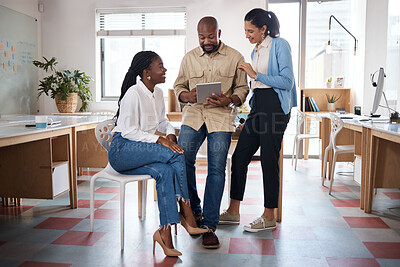 Buy stock photo Shot of a group of businesspeople using a digital tablet while having a discussion in a modern office