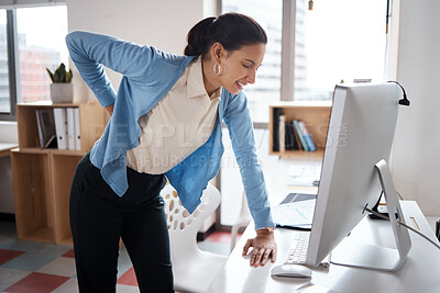 Buy stock photo Shot of a young businesswoman experiencing back pain while working at her desk in a modern office