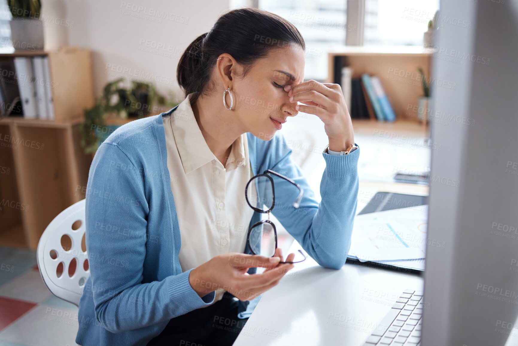 Buy stock photo Shot of a young businesswoman looking stressed while using a laptop at her desk in a modern office