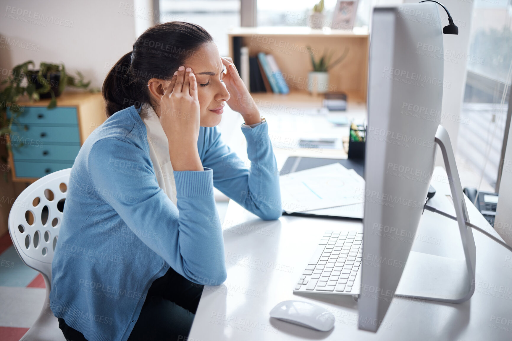 Buy stock photo Shot of a young businesswoman looking stressed while using a laptop at her desk in a modern office