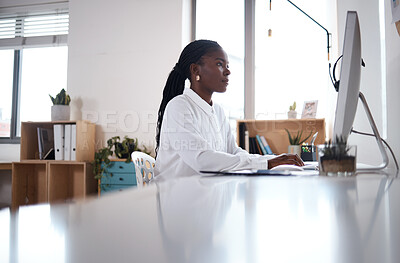 Buy stock photo Shot of a young businesswoman using a computer at her desk in a modern office