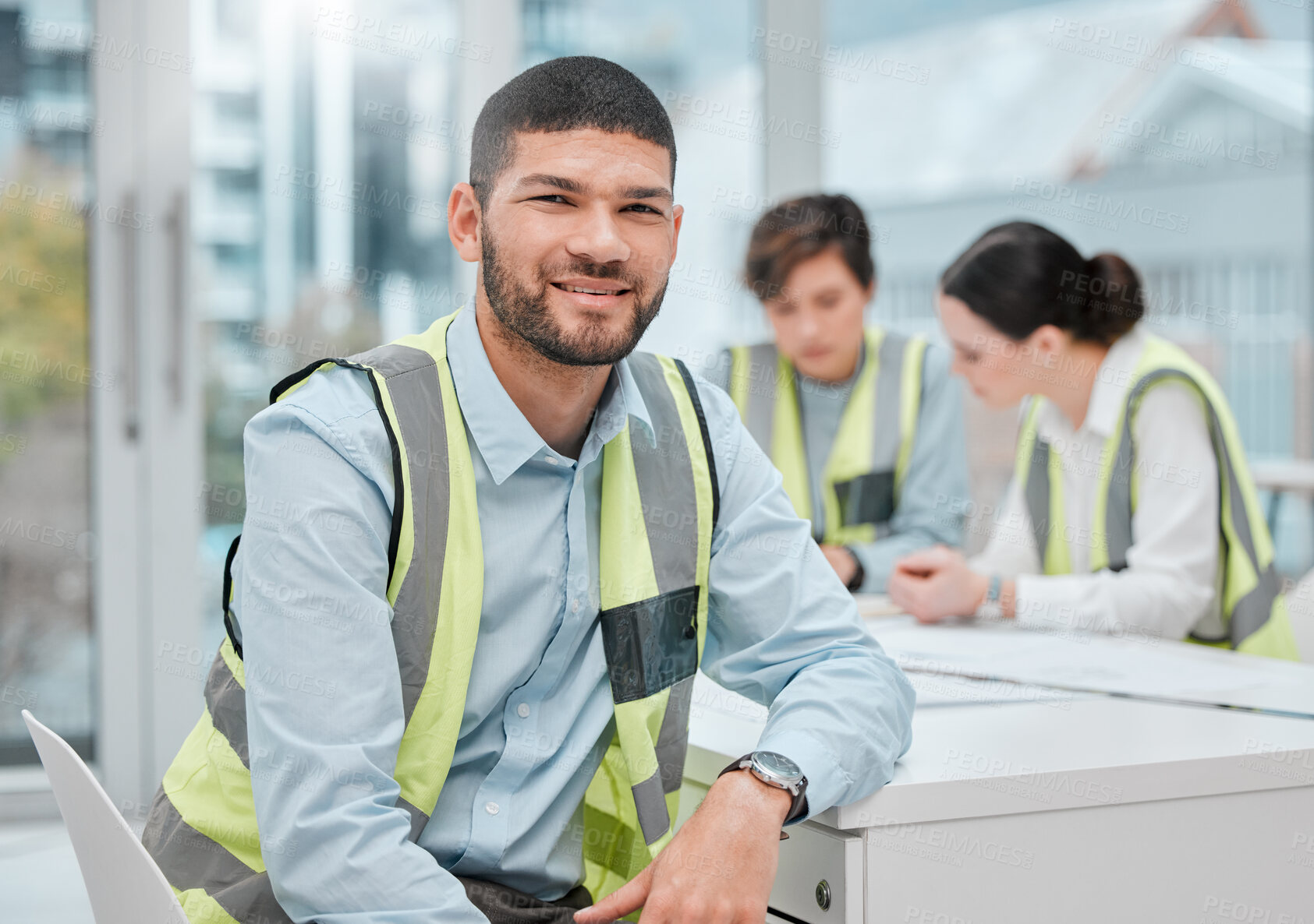 Buy stock photo Cropped portrait of a handsome young male construction worker sitting in a meeting with his colleagues