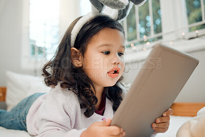 Buy stock photo App, education and tablet with girl child in bedroom of home for information, reading or storytelling. Ebook, gaming and relax with adorable kid on bed in apartment for internet browsing or streaming