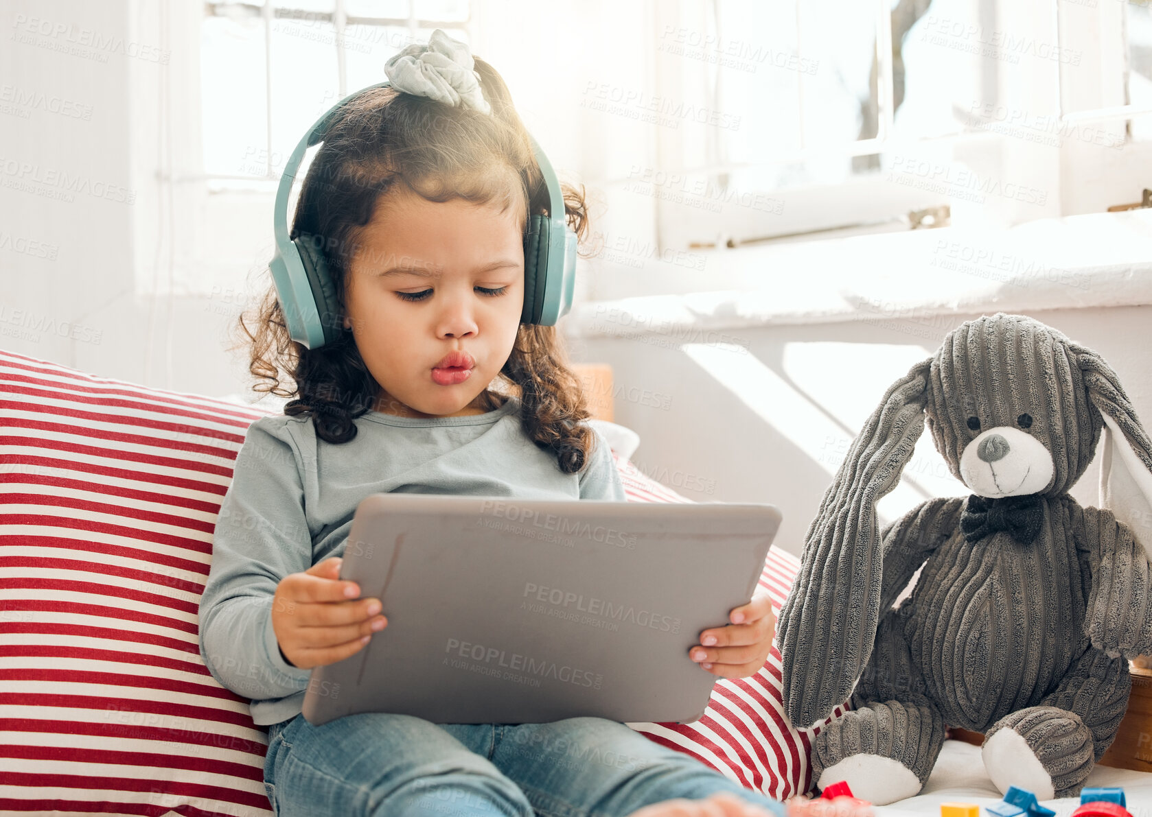 Buy stock photo Education, music and tablet with girl child in bedroom of home for information, reading or storytelling. Ebook, education and headphones with adorable kid in apartment for app or web or streaming