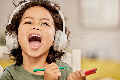 Buy stock photo Shot of a little boy drawing while listening to music at home