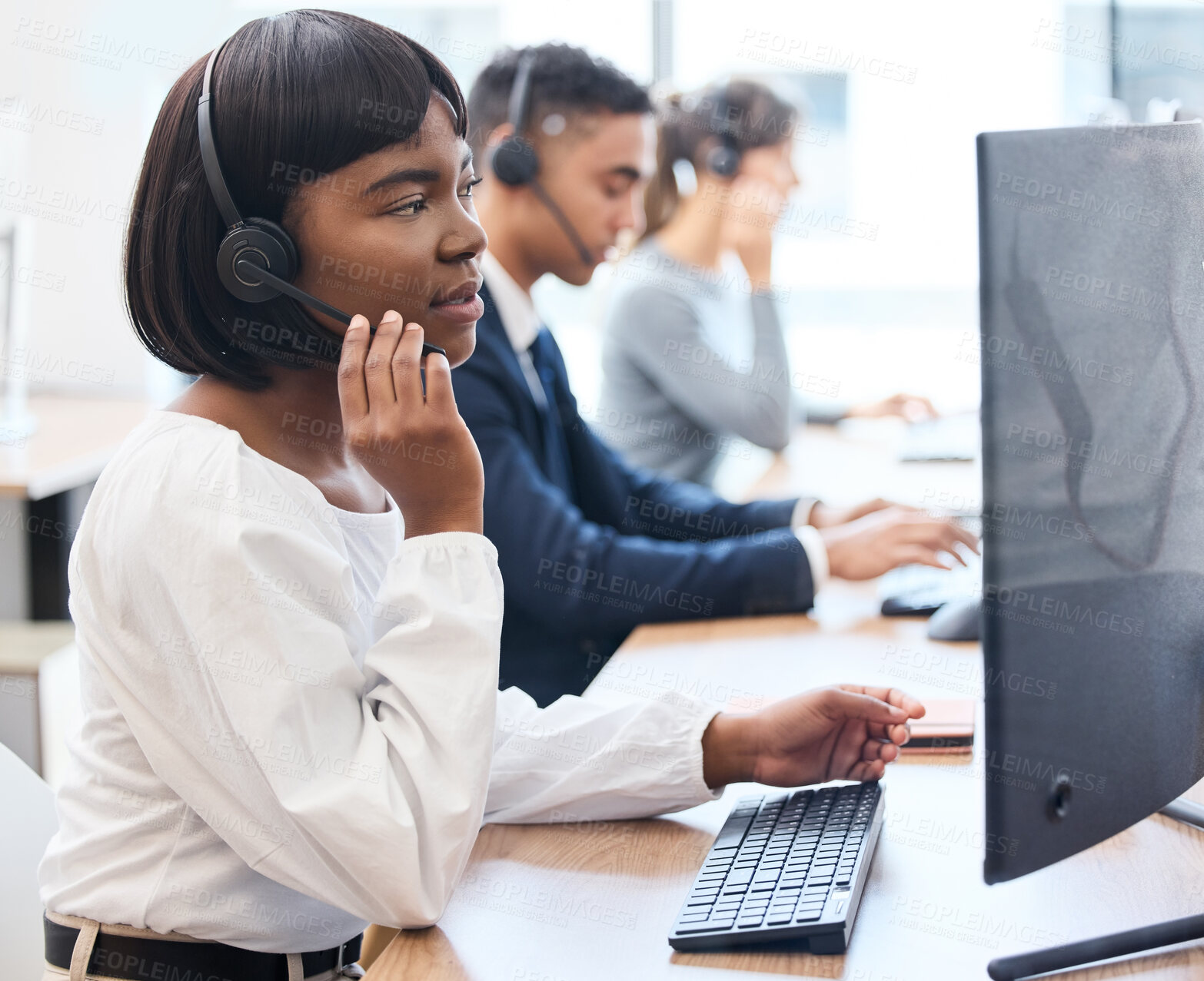 Buy stock photo Call center, desk and black woman with headset, talking and customer service in office and hand. CRM, telemarketing and person with tech support, speaking and agent in agency and work with computer