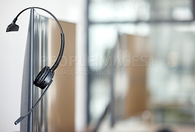 Buy stock photo Closeup shot of a headset hanging on a computer screen in an office