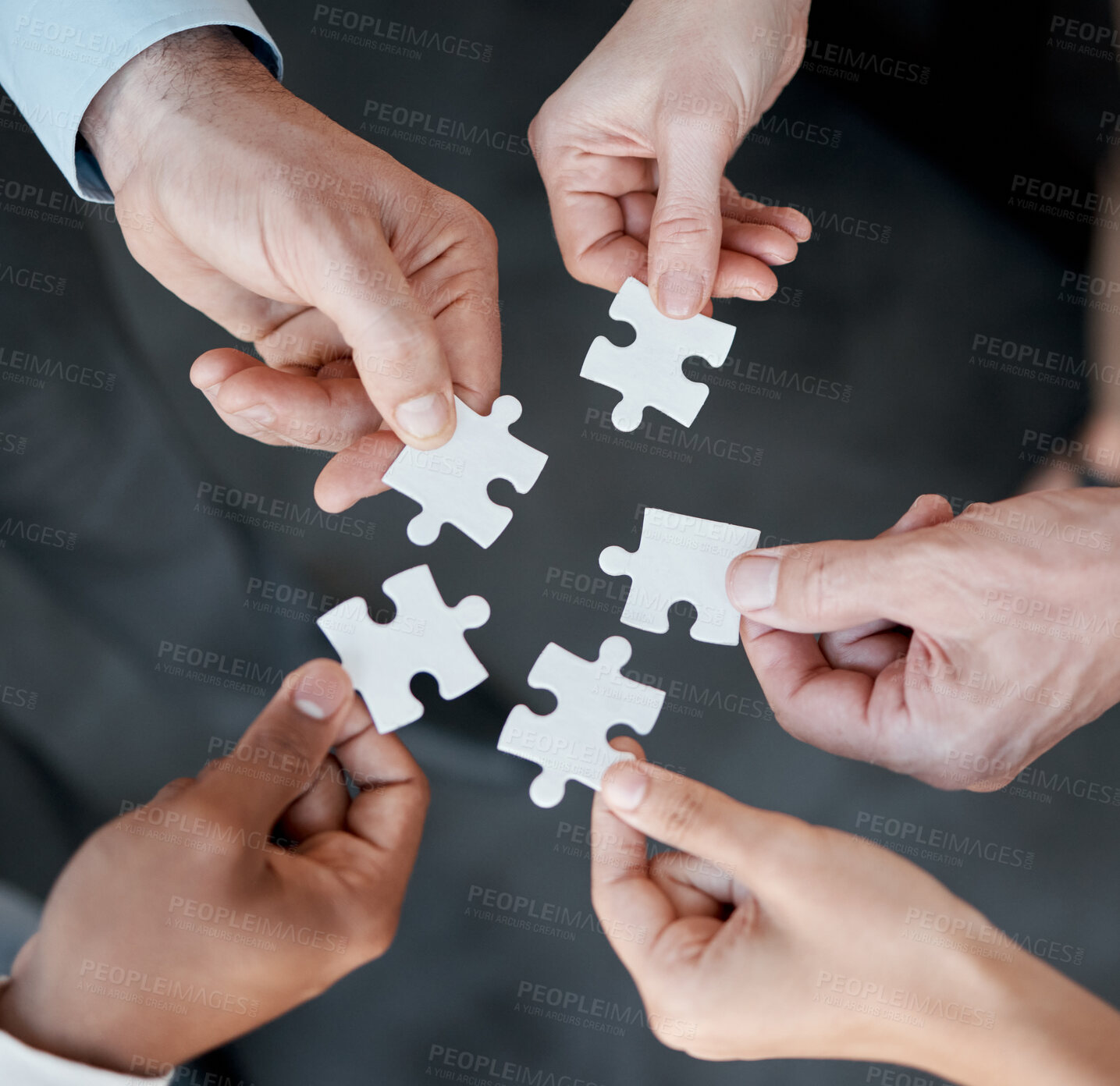 Buy stock photo Cropped shot of five unrecognizable businesspeople building a puzzle in the office