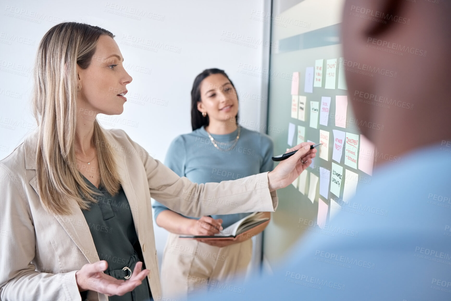 Buy stock photo Shot of a group of businesspeople brainstorming with sticky notes on a chalkboard