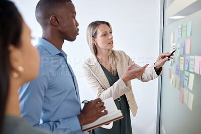 Buy stock photo Shot of a group of businesspeople brainstorming with sticky notes on a chalkboard