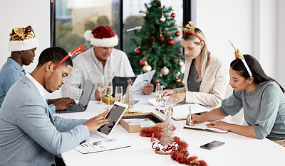 Buy stock photo Shot of a group of businesspeople working together in a boardroom while wearing Christmas hats