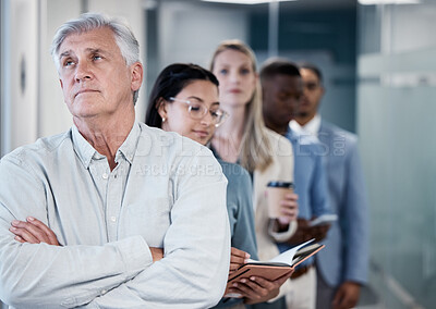 Buy stock photo Shot of a mature businessman standing with his arms crossed while waiting in line in an office