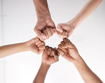 Buy stock photo Low angle shot of a group of businesspeople joining their fists in solidarity