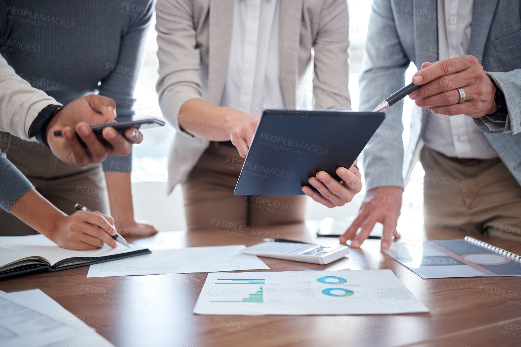 Buy stock photo Cropped shot of a group of unrecognizable businesspeople looking over a tablet in the boardroom