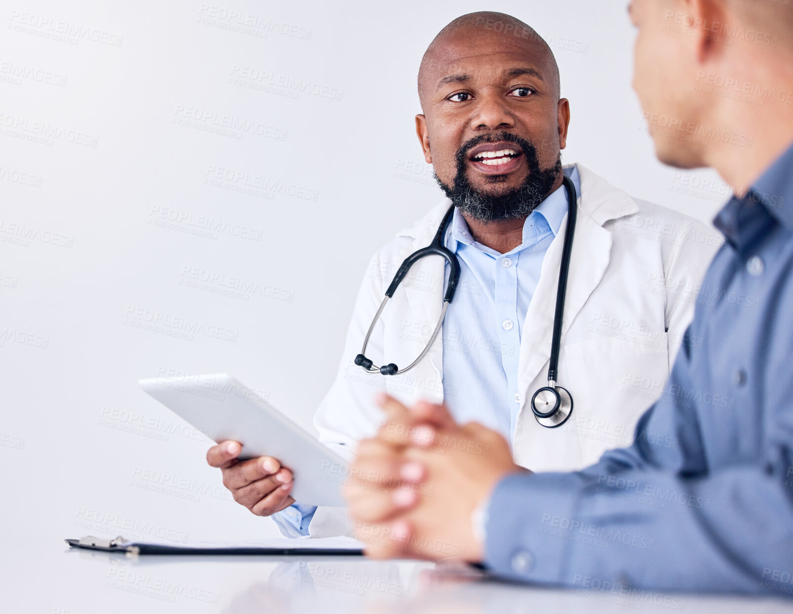 Buy stock photo Shot of a mature male doctor using a digital tablet during a consultation at a clinic