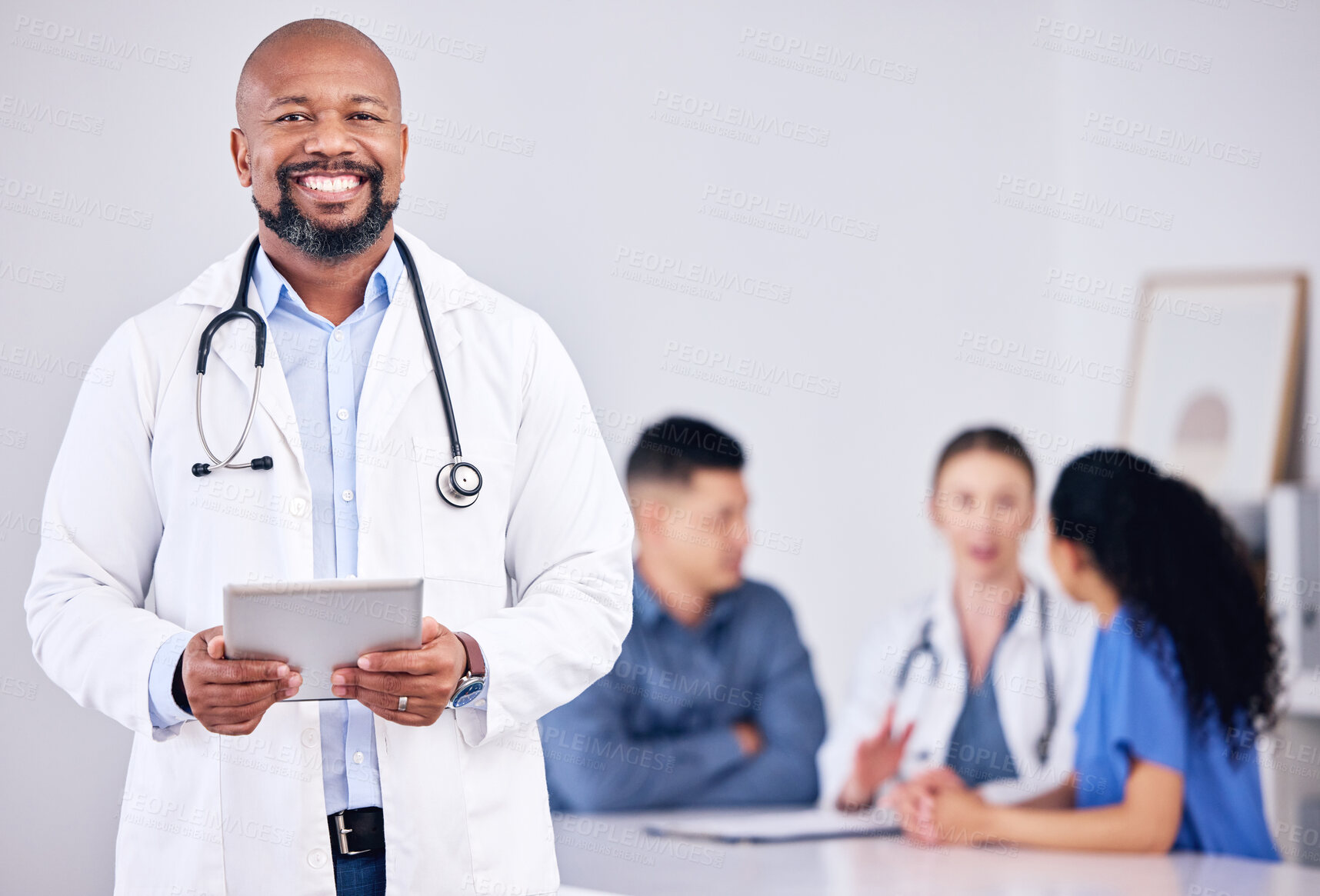 Buy stock photo Shot of a mature male doctor using a digital tablet during a consultation at a clinic