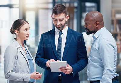 Buy stock photo Shot of a group of businesspeople using a digital tablet at work