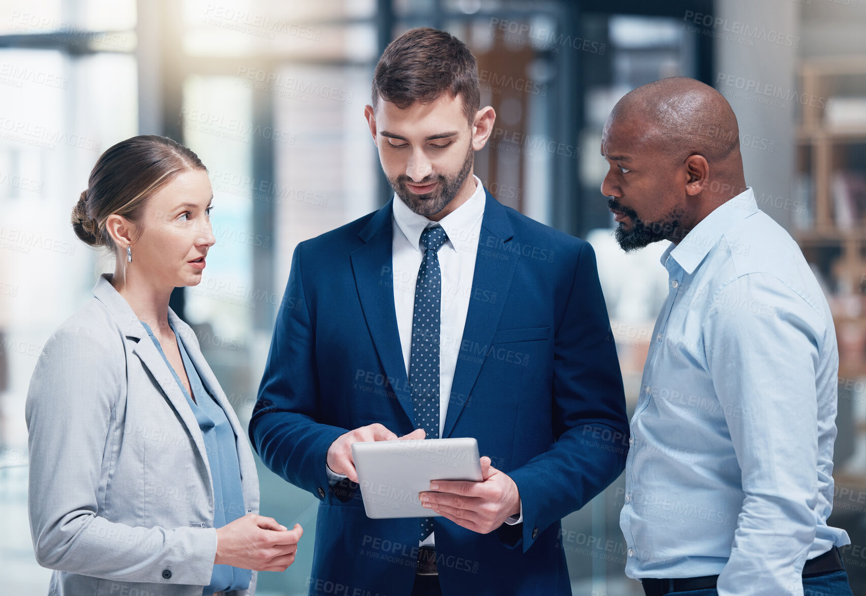 Buy stock photo Shot of a group of businesspeople using a digital tablet at work