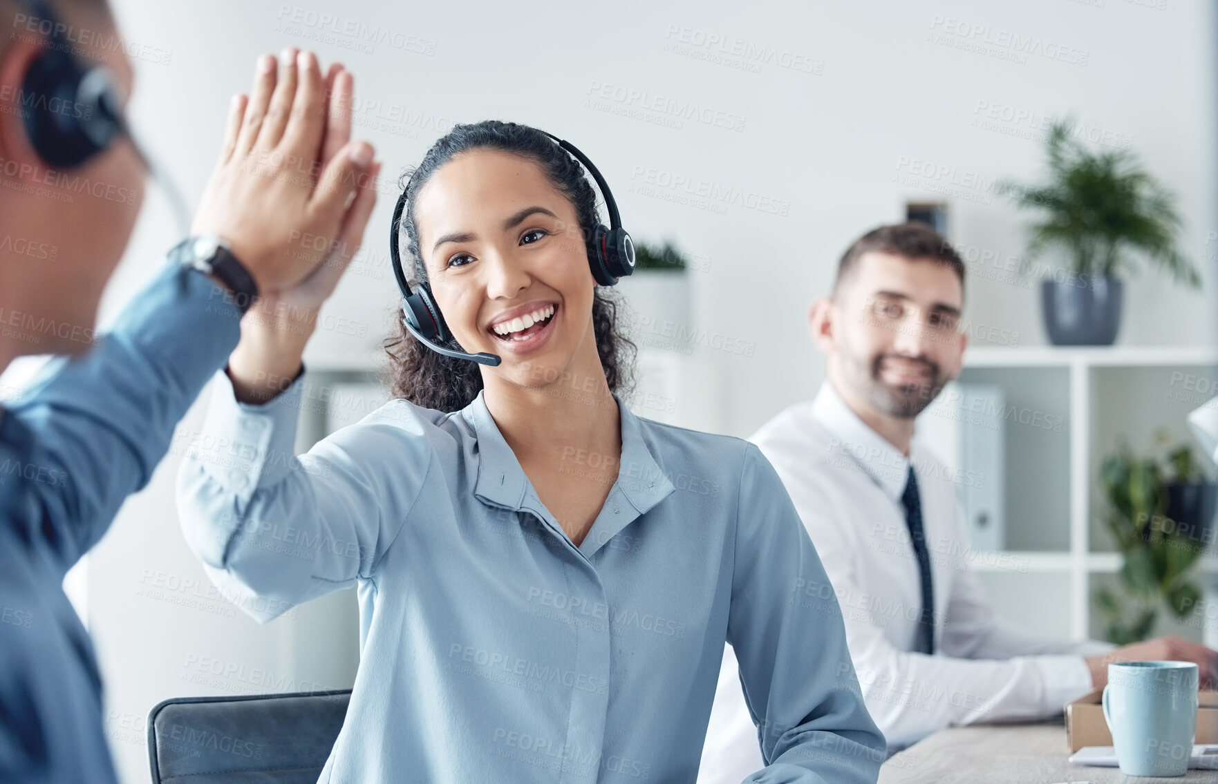 Buy stock photo Shot of two call centre agents giving each other a high five in an office