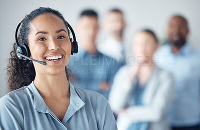 Buy stock photo Portrait of a young call centre agent standing in an office with her colleagues in the background